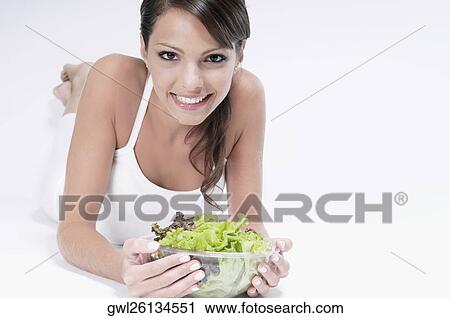 Woman lying with a bowl of salad in her hands View Large Photo Image Stock Image - Woman lying with a bowl of salad in her hands. Fotosearch