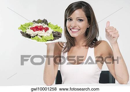 Woman making a thumbs up sign with a plate of salad View Large Photo Image Stock Photo - Woman making a thumbs up sign with a plate of salad. Fotosearch