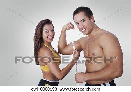 Woman measuring biceps of a man with a tape measure View Large Photo Image Stock Image - Woman measuring biceps of a man with a tape measure. Fotosearch