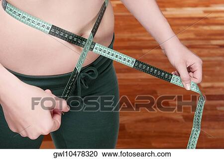Woman measuring her waist with a tape measure View Large Photo Image Stock Image - Woman measuring her waist with a tape measure. Fotosearch