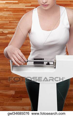 Woman measuring her weight on a weighing scale View Large Photo Image Stock Photograph - Woman measuring her weight on a weighing scale. Fotosearch