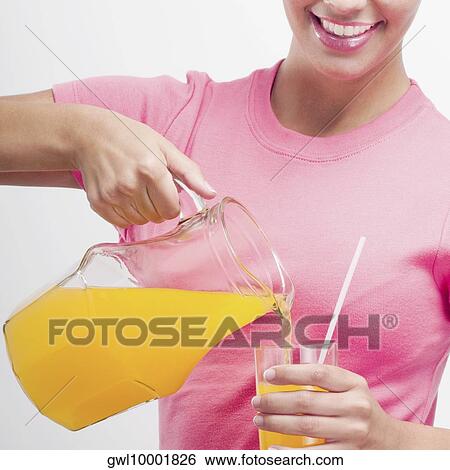 Woman pouring orange juice from a jug View Large Photo Image Stock Photograph - Woman pouring orange juice from a jug. Fotosearch