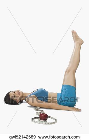Stock Photo - Woman practicing yoga near a measuring tape and red apple. Fotosearch