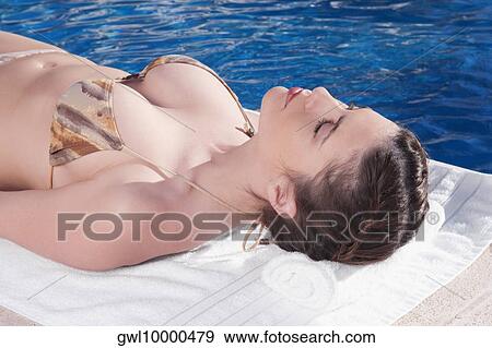 Stock Photo - Woman resting by a swimming pool. Fotosearch