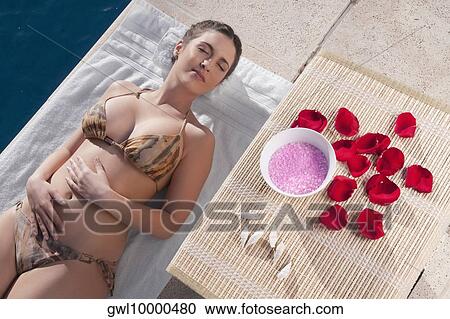 Woman resting with aroma products beside her at the poolside View Large Photo Image Stock Image - Woman resting with aroma products beside her at the poolside. Fotosearch
