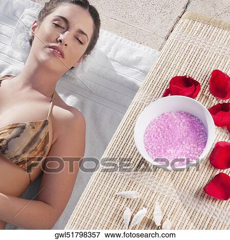 Stock Photo - Woman resting with aroma products beside her at the poolside. Fotosearch