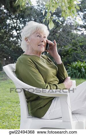 Woman sitting in a chair and talking on a mobile phone View Large Photo Image Stock Photo - Woman sitting in a chair and talking on a mobile phone. Fotosearch