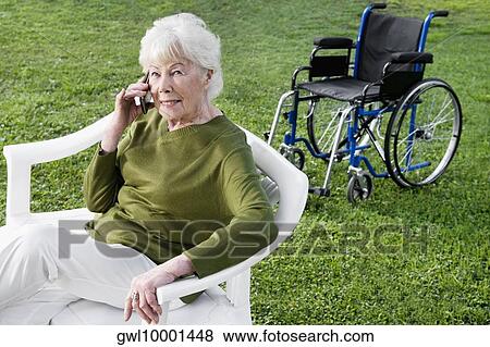 Woman sitting in a park and using a mobile phone View Large Photo Image Stock Photo - Woman sitting in a park and using a mobile phone. Fotosearch