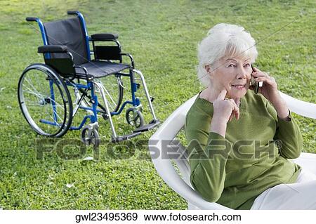 Woman sitting in a park and using a mobile phone View Large Photo Image Stock Photo - Woman sitting in a park and using a mobile phone. Fotosearch
