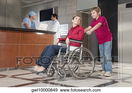 Woman sitting in a wheelchair being pushed by her son View Large Photo Image Stock Photo - Woman sitting in a wheelchair being pushed by her son. Fotosearch