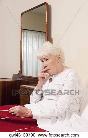 Woman sitting on the bed and looking serious View Large Photo Image Stock Image - Woman sitting on the bed and looking serious. Fotosearch