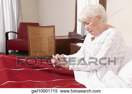 Woman sitting on the bed and looking serious View Large Photo Image Stock Photography - Woman sitting on the bed and looking serious. Fotosearch