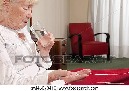 Woman sitting on the bed and taking medicine View Large Photo Image Stock Image - Woman sitting on the bed and taking medicine. Fotosearch