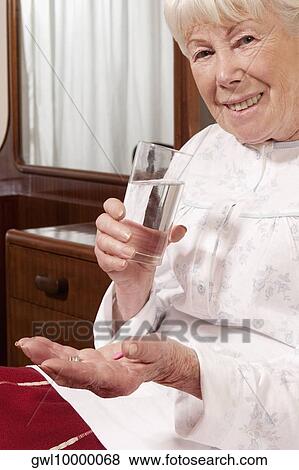 Woman sitting on the bed and taking medicine View Large Photo Image Stock Photo - Woman sitting on the bed and taking medicine. Fotosearch