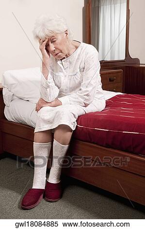 Stock Photography - Woman sitting on the bed with head in hands. Fotosearch