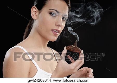 Picture - Woman smelling a burning incense cone. Fotosearch