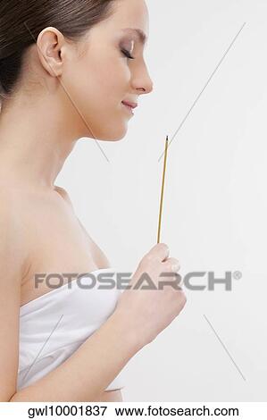 Stock Photo - Woman smelling a burning incense stick. Fotosearch