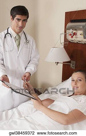 Woman taking clipboard from a doctor in a hospital View Large Photo Image Stock Image - Woman taking clipboard from a doctor in a hospital. Fotosearch