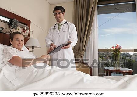 Woman taking clipboard from a doctor in a hospital View Large Photo Image Stock Photo - Woman taking clipboard from a doctor in a hospital. Fotosearch