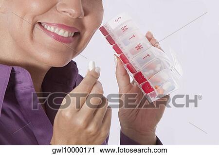 Stock Image - Woman taking medicine from a pill box. Fotosearch