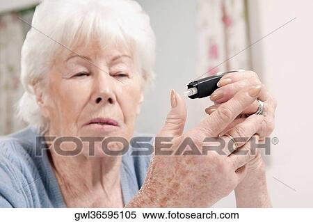Stock Photography - Woman testing her blood sugar level. Fotosearch