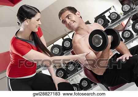 Woman touching a man's bicep as he exercising with a dumbbell View Large Photo Image Stock Image - Woman touching a man's bicep as he exercising with a dumbbell. Fotosearch