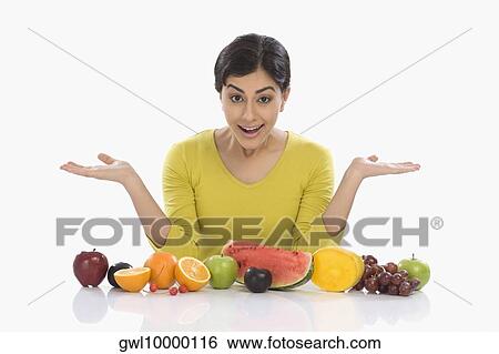 Stock Photograph - Woman with assorted fresh fruits and gesturing. Fotosearch