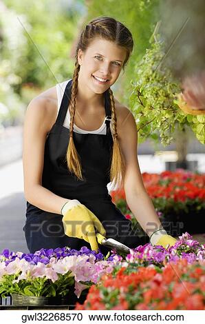 Stock Image - Woman working in a greenhouse and smiling. Fotosearch