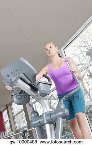 Woman working out on a stepping machine in a gym View Large Photo Image Stock Photo - Woman working out on a stepping machine in a gym. Fotosearch