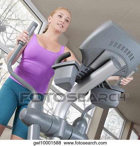 Woman working out on a stepping machine in a gym View Large Photo Image Stock Photo - Woman working out on a stepping machine in a gym. Fotosearch