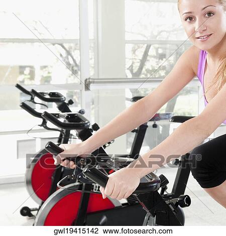 Woman working out on an exercise bike in a gym View Large Photo Image Stock Image - Woman working out on an exercise bike in a gym. Fotosearch