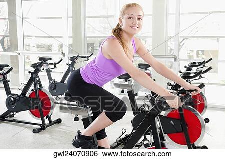 Woman working out on an exercise bike in a gym View Large Photo Image Stock Photograph - Woman working out on an exercise bike in a gym. Fotosearch