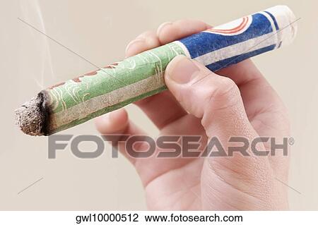Stock Image - Woman's hand holding a herbal cigar. Fotosearch