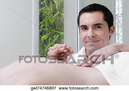 Stock Photo - Acupuncturist applying needles on a person's back. Fotosearch