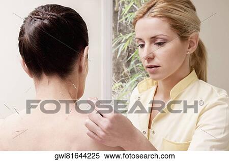 Stock Photography - Acupuncturist applying needles on a woman's back. Fotosearch