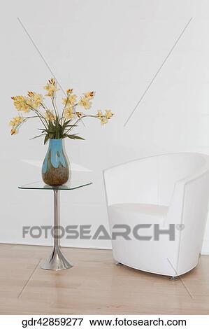 Stock Photo - Armchair with a flower vase in a room. Fotosearch