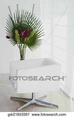Stock Photo - Armchair with a houseplant in a room. Fotosearch