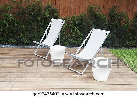 Chairs with stools on the floorboard in a garden View Large Photo Image Stock Image - Chairs with stools on the floorboard in a garden. Fotosearch