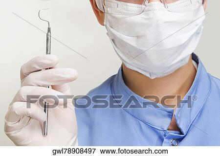 Close-up of a female dentist holding a dental scaler View Large Photo Image Stock Photo - Close-up of a female dentist holding a dental scaler. Fotosearch
