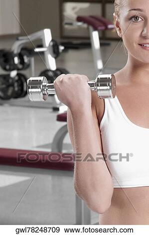 Close-up of a woman exercising with dumbbells at gym View Large Photo Image Stock Photo - Close-up of a woman exercising with dumbbells at gym. Fotosearch