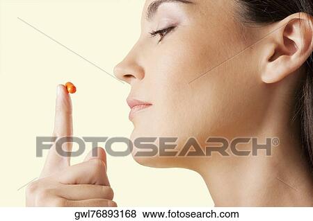 Close-up of a woman looking at a capsule View Large Photo Image Stock Photo - Close-up of a woman looking at a capsule. Fotosearch