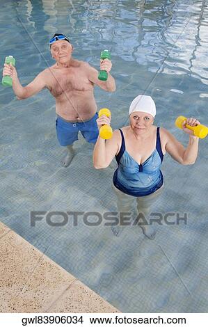 Couple exercising with dumbbells in a swimming pool View Large Photo Image Picture - Couple exercising with dumbbells in a swimming pool. Fotosearch