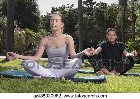 Couple practicing yoga in a park View Large Photo Image Stock Image - Couple practicing yoga in a park. Fotosearch
