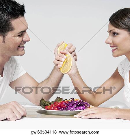 Couple squeezing orange halves over a salad View Large Photo Image Stock Photo - Couple squeezing orange halves over a salad. Fotosearch