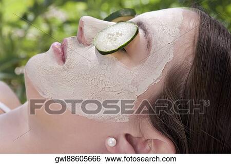 Stock Photograph - Cucumber slices on a woman's eyes. Fotosearch