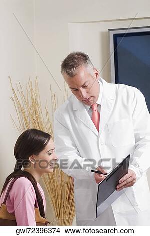 Picture - Dentist discussing with his patient. Fotosearch