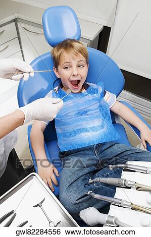 Dentist examining a boy's teeth View Large Photo Image Stock Photograph - Dentist examining a boy's teeth. Fotosearch