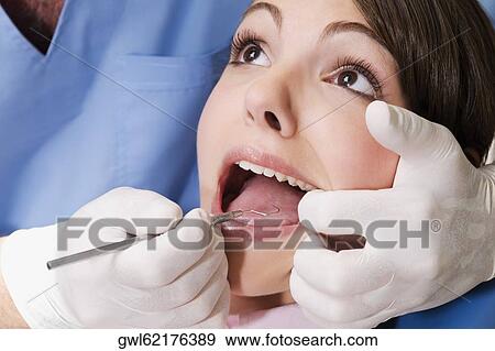 Dentist examining a woman's teeth View Large Photo Image Stock Photo - Dentist examining a woman's teeth. Fotosearch