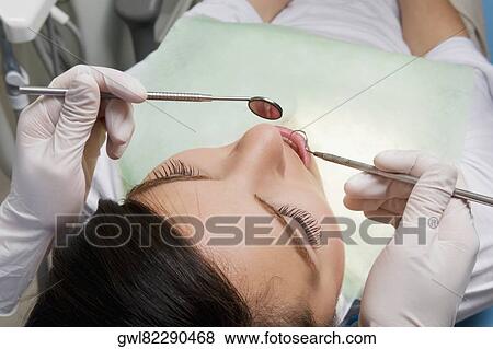 Dentist examining a woman's teeth View Large Photo Image Stock Photo - Dentist examining a woman's teeth. Fotosearch