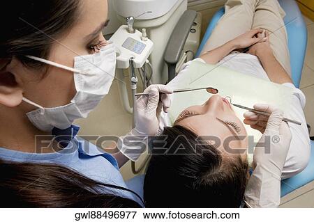 Dentist examining a woman's teeth View Large Photo Image Stock Photo - Dentist examining a woman's teeth. Fotosearch